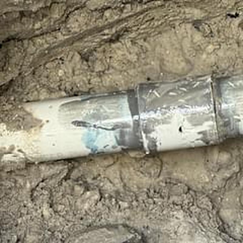 PVC pressure pipe coupling with visible crack in soil trench