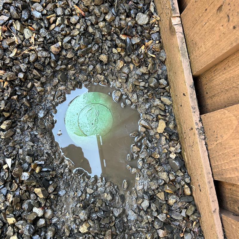 Pop-up storm drain head amid gravel near wooden frame Pop-up storm drain head amid gravel near wooden frame