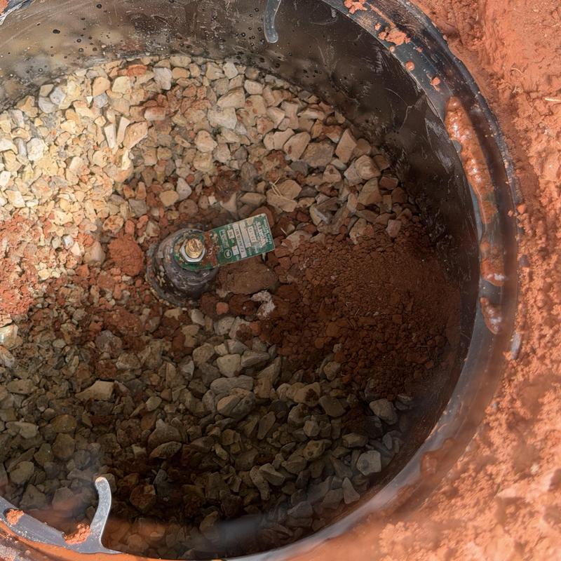 Water meter valve surrounded by gravel and red soil Water meter valve surrounded by gravel and red soil