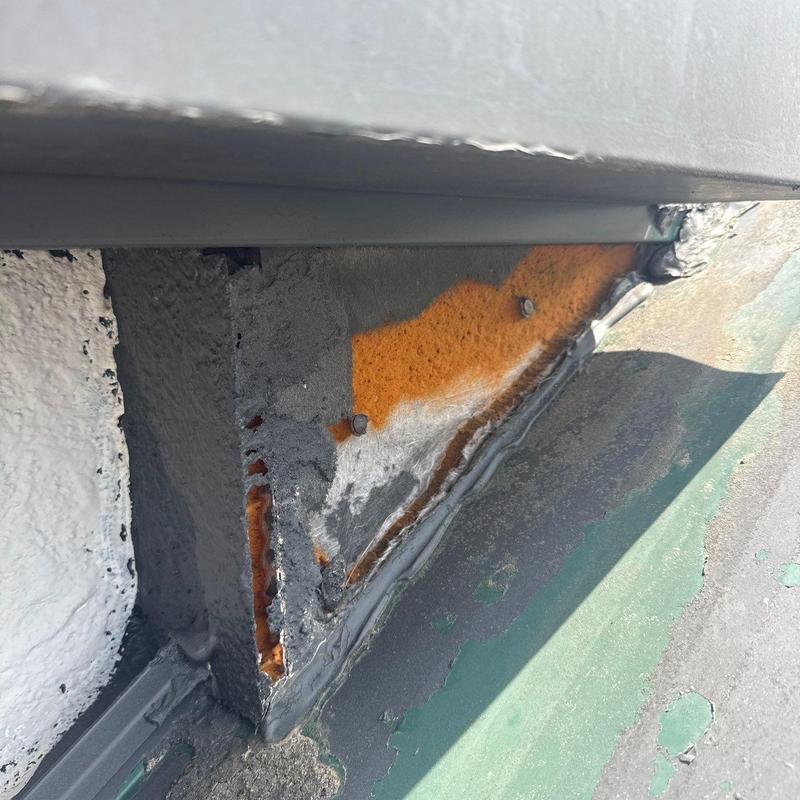 Metal roof flashing with rust and sealant damage