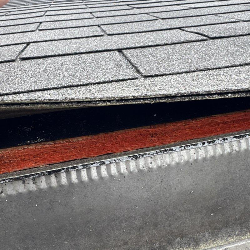 Asphalt shingles with hail damage close-up on roof edge