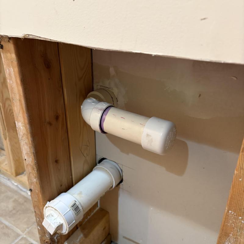 PVC drain line with end caps mounted in wall cavity