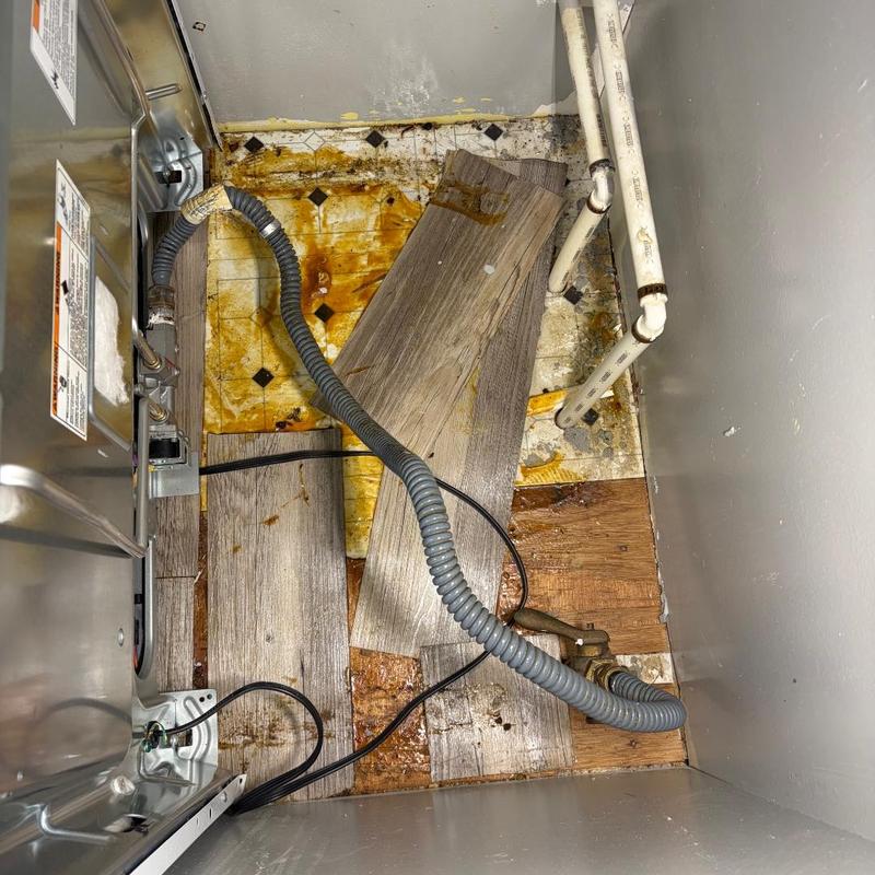 Gas pipe and valve under stove with rusted floor