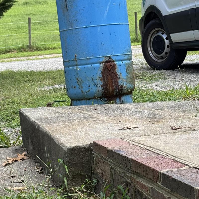 Well pressure tank with rust stains outside home Well pressure tank with rust stains outside home
