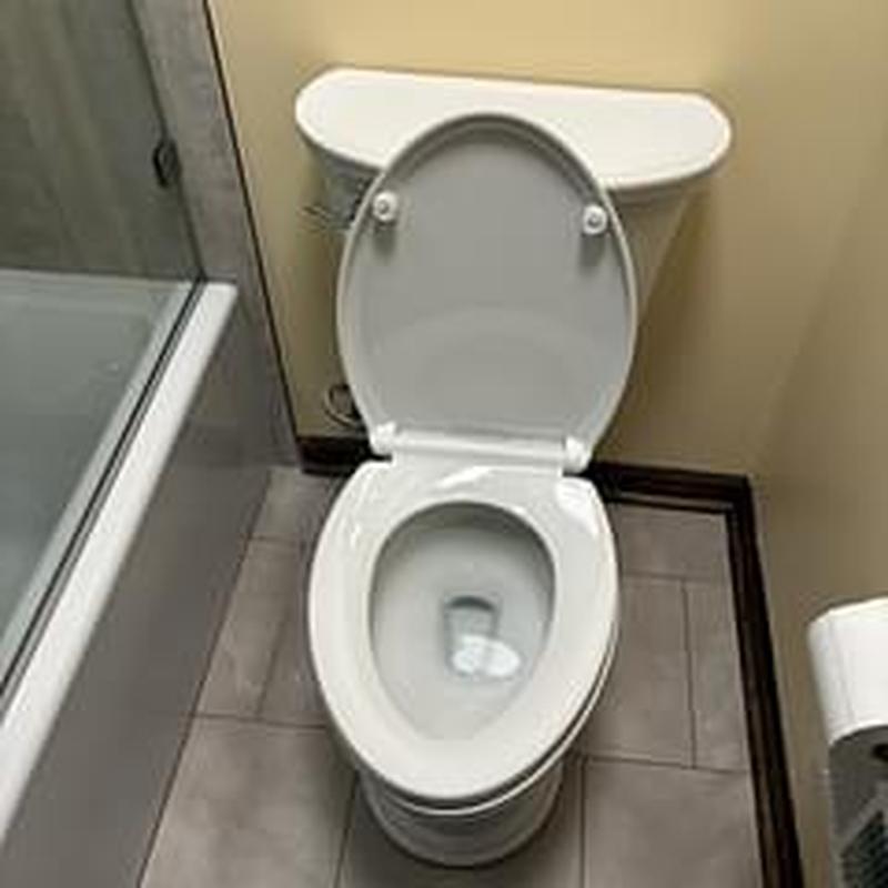 Toilet with open lid in bathroom near tub Toilet with open lid in bathroom near tub