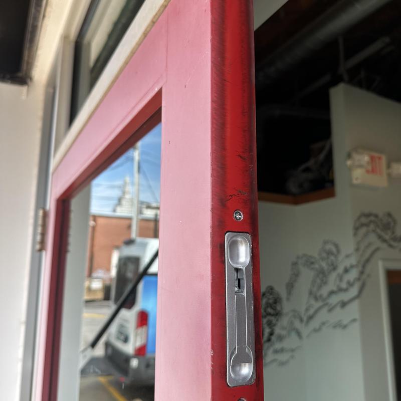Flush bolts on red inactive glass door frame Flush bolts on red inactive glass door frame