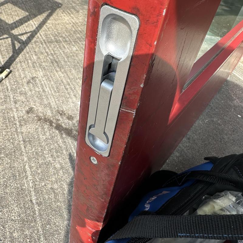 Flush bolt installed on red inactive glass door edge Flush bolt installed on red inactive glass door edge