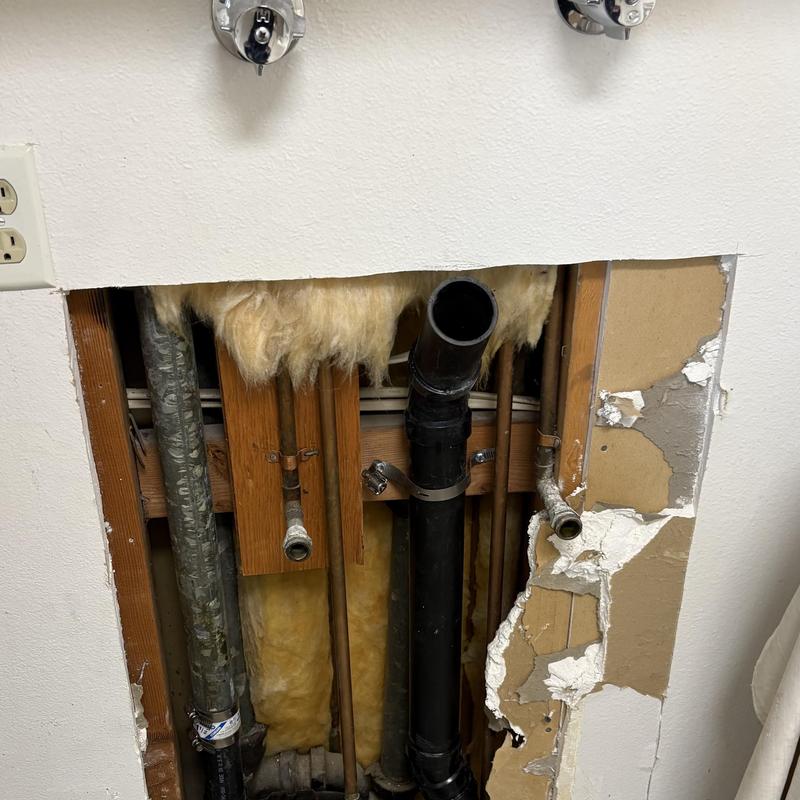 Laundry drain pipe with exposed drywall and insulation