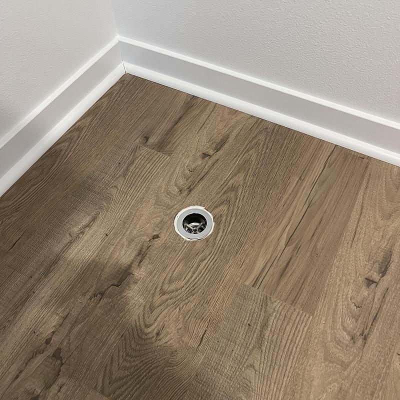 Drain spud with rubber seal and putty on wood floor