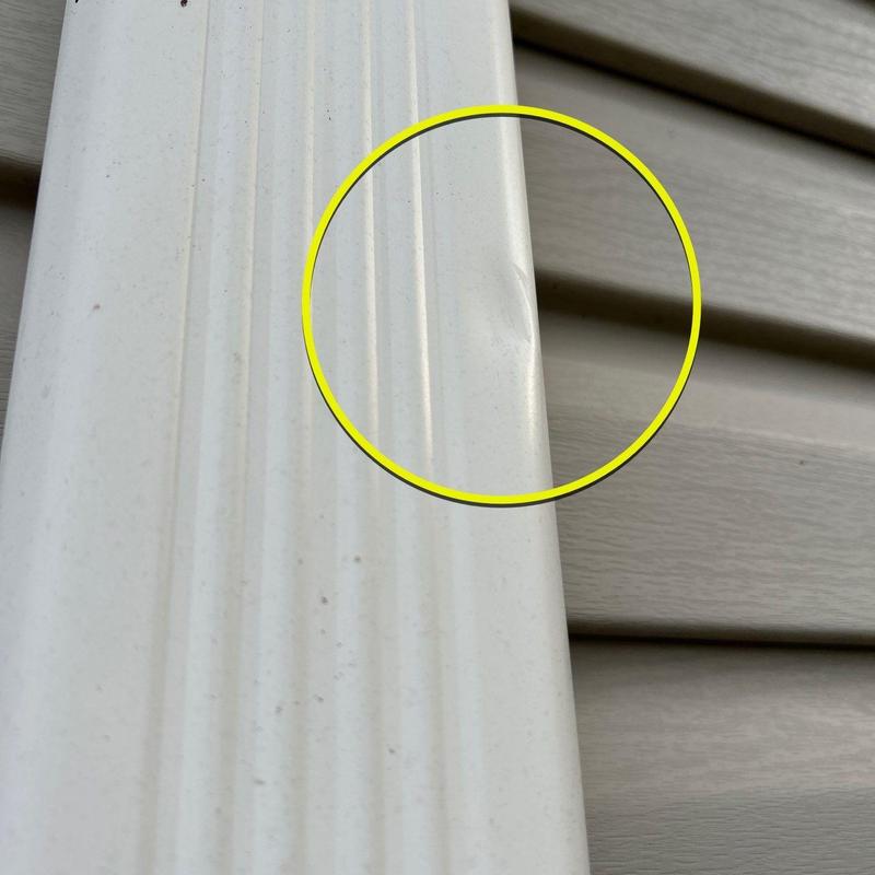 Vinyl siding dent marked with yellow circle