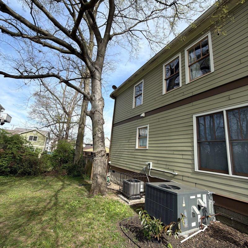 Air conditioning unit beside house exterior and yard