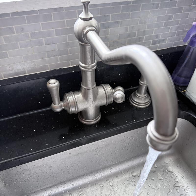 Kitchen faucet with water flowing on black countertop
