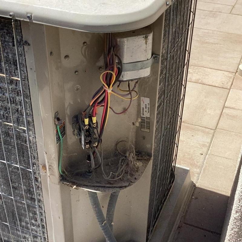 Air conditioner wiring compartment with exposed cables and debris