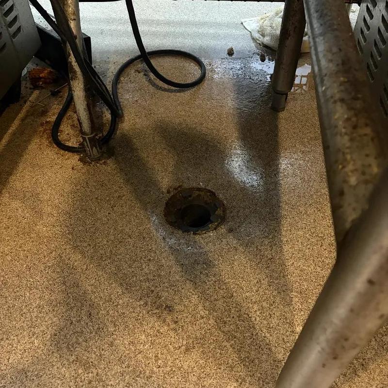 Floor drain with plumbing snake tool nearby