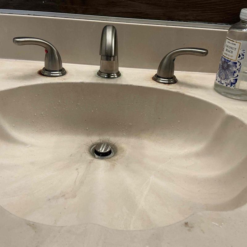 Bathroom faucet and sink with water spots and hair