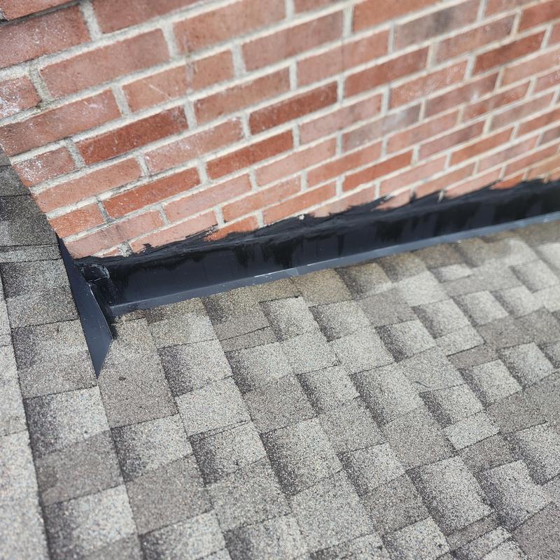 Chimney flashing with black sealant on asphalt roof Chimney flashing with black sealant on asphalt roof