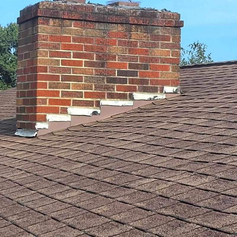 Chimney flashing and aged shingle roof with wear