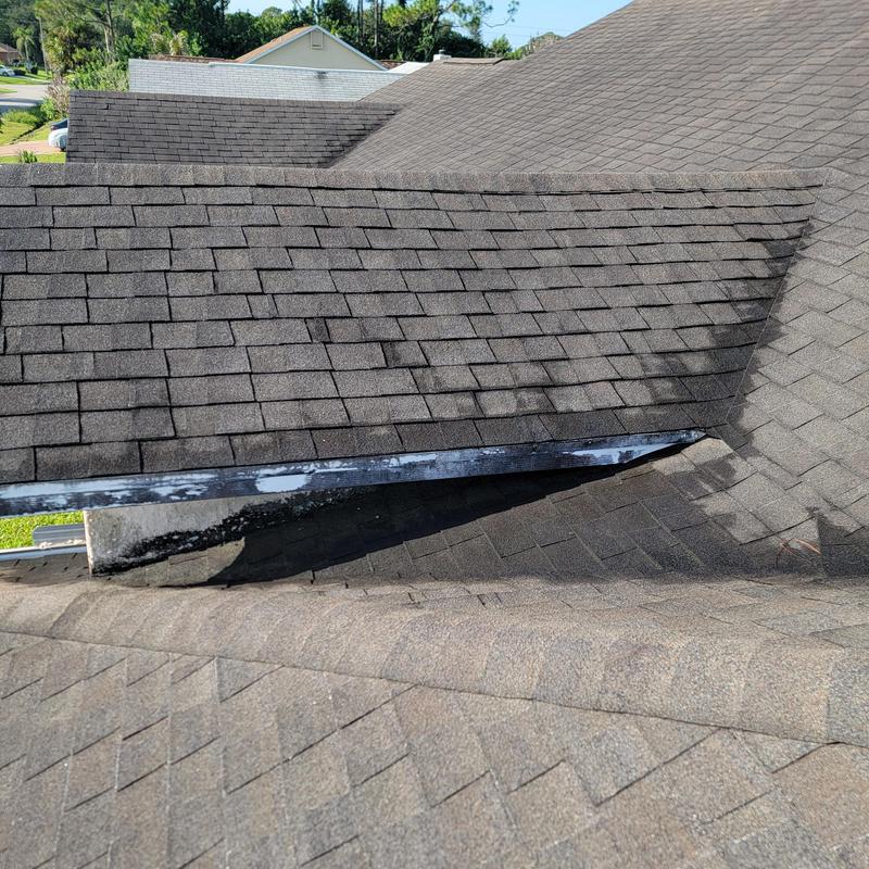 Asphalt shingle roof section with visible flashing and wear Asphalt shingle roof section with visible flashing and wear