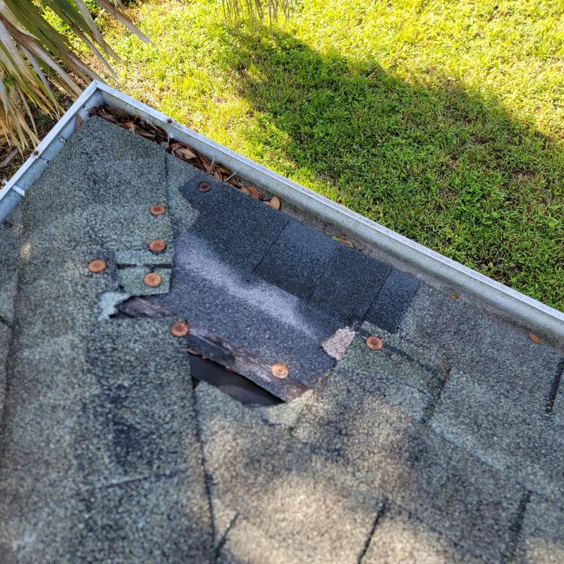 Roof shingles with missing and damaged sections near gutter Roof shingles with missing and damaged sections near gutter