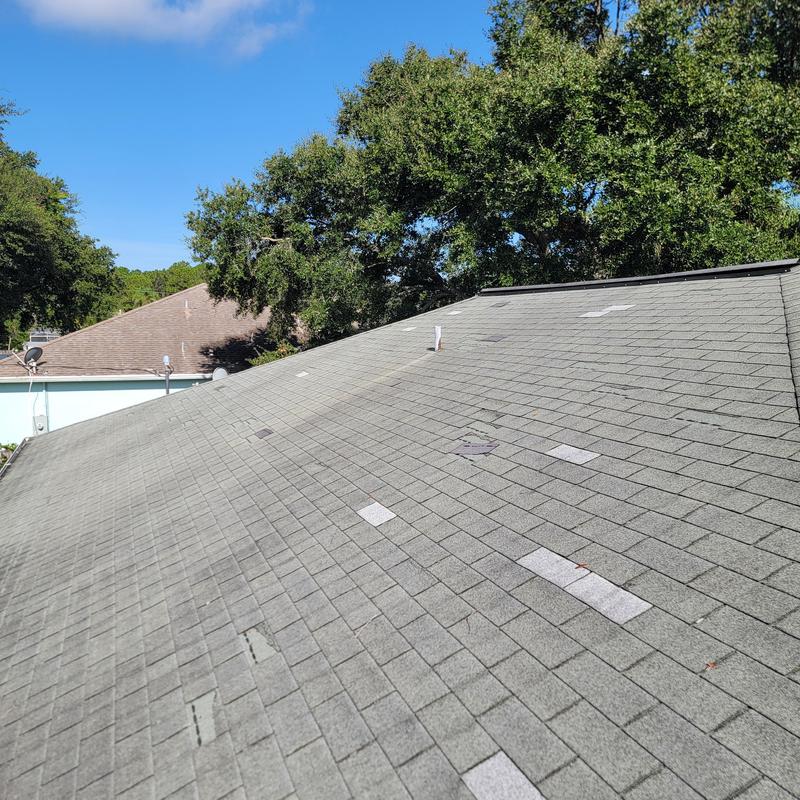 Three-tab shingle roof with missing patches and wear Three-tab shingle roof with missing patches and wear