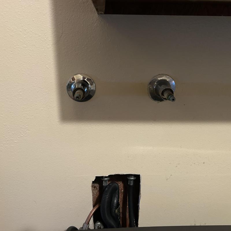 Laundry water valves with exposed plumbing behind drywall
