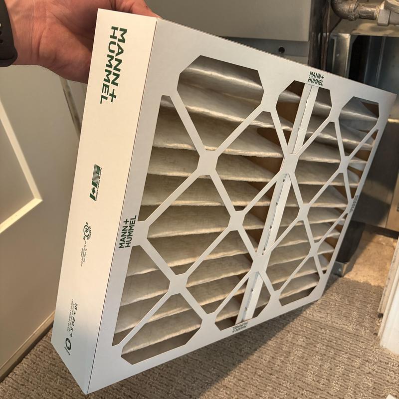 HVAC air filter being held near furnace unit