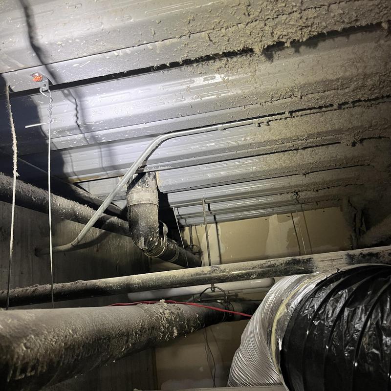 HVAC ductwork with insulation and pipes in ceiling cavity
