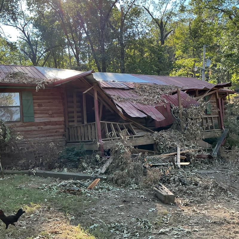 Collapsed porch and roof damage on wooden house