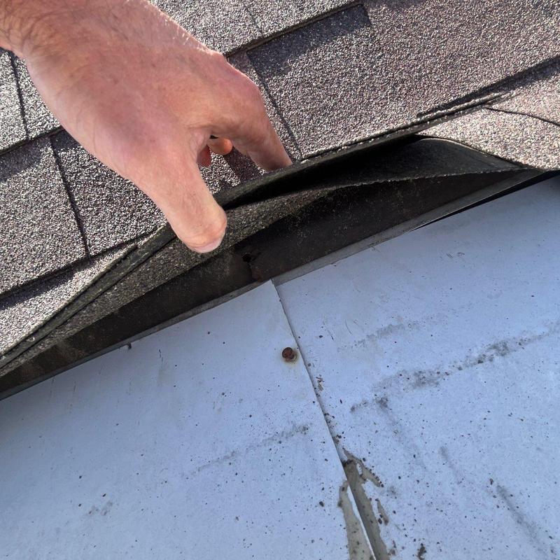 Asphalt roofing shingles lifted to show underlying roof surface