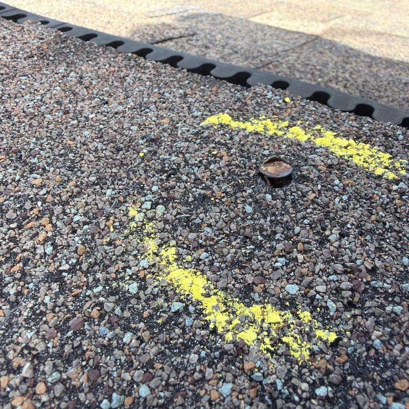 Asphalt roof shingle with hail impact damage marked in yellow