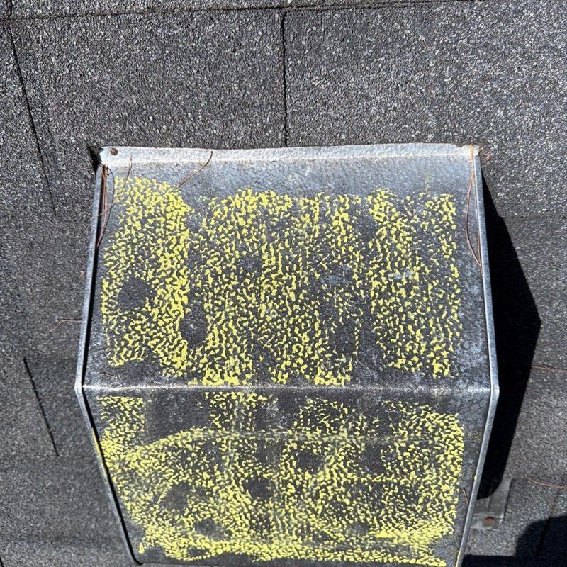 Roof vent with yellow corrosion spots on shingle roof