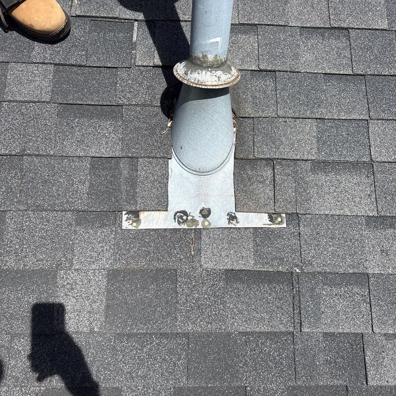 Roof shingles around metal vent pipe flashing on shingled roof