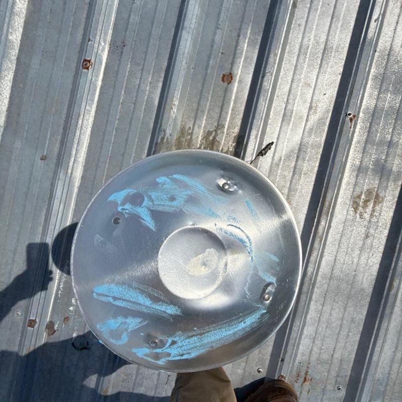 Metal exhaust vent with hail impact marks on roof panel