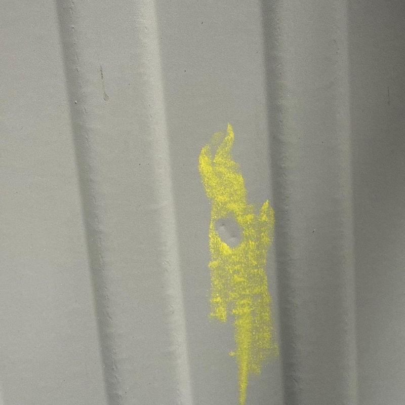 Metal roof panel with hail damage marked in yellow