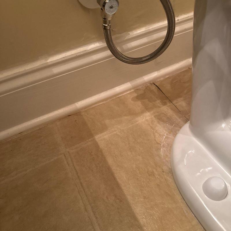 Toilet base with cracked bathroom floor tile and water stain