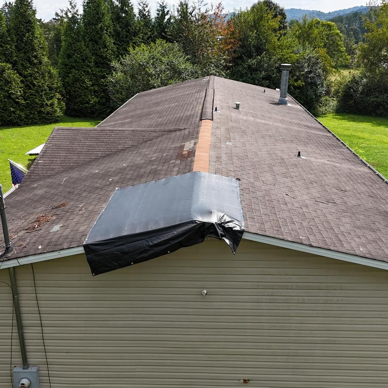 Asphalt shingle roof with temporary tarp covering Asphalt shingle roof with temporary tarp covering