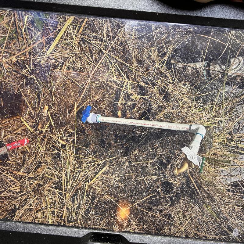 Outdoor hose bibb with PVC water line on dry grass Outdoor hose bibb with PVC water line on dry grass