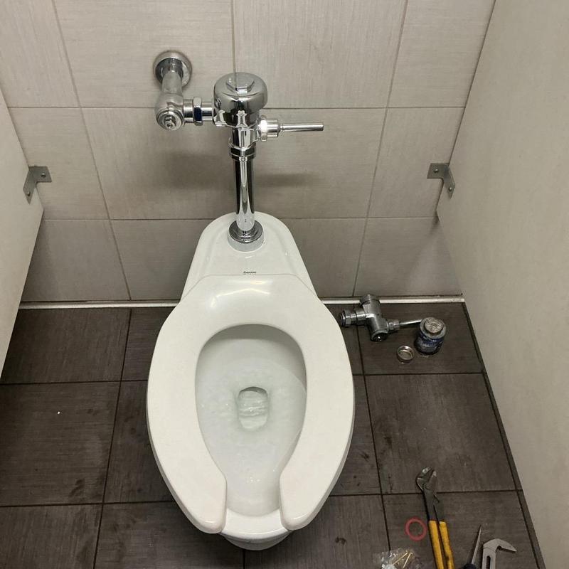 Flushometer toilet with tools and parts on floor Flushometer toilet with tools and parts on floor