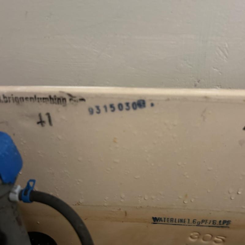 Toilet tank interior showing flushing mechanism and waterline label