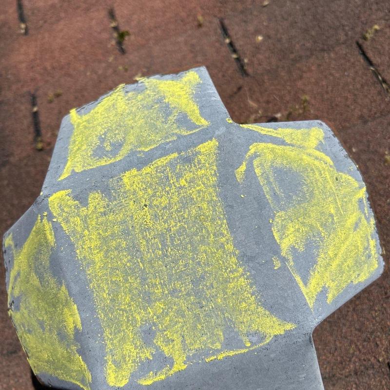 Asphalt roof shingle with yellow chalk marking hail damage