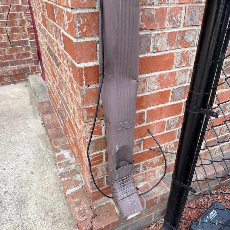 Downspout extension with damage on brick wall