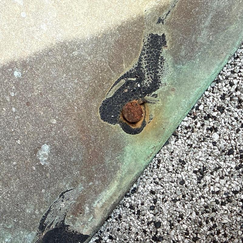 Metal roof panel with rusted fastener and corrosion
