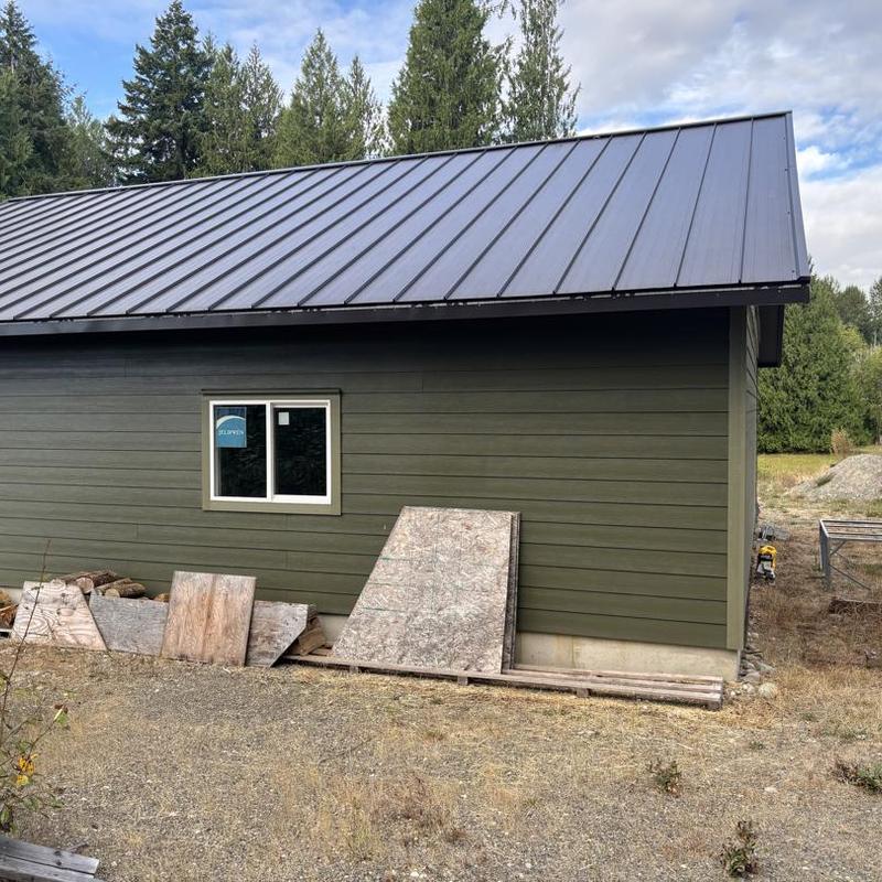 Roof metal panel installation on green siding building