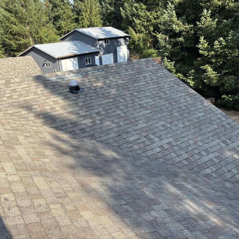 Asphalt shingle roof with vent and nearby metal roofs