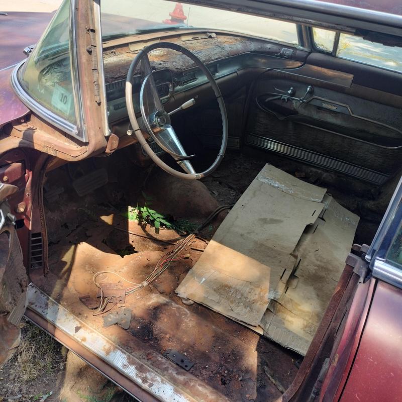 Classic car interior with steering wheel and rusty floor