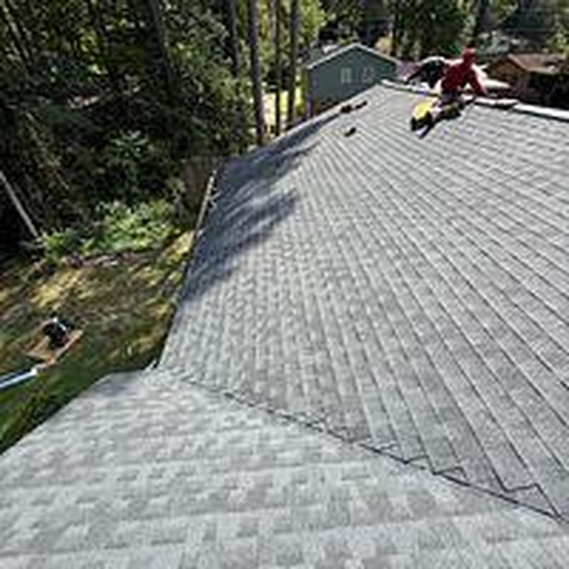 Asphalt shingle roof with worker installing shingles Asphalt shingle roof with worker installing shingles