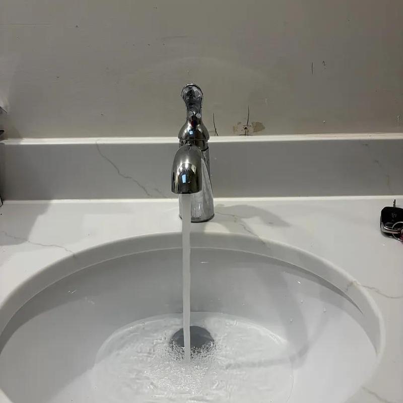 Bathroom faucet with running water in white sink