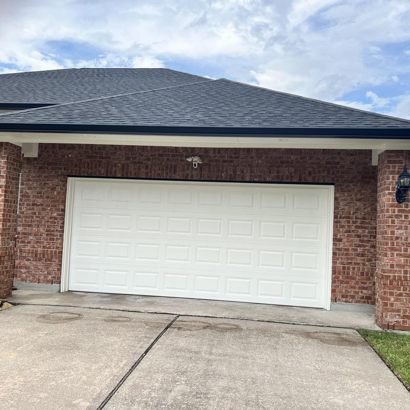 Garage door with white panel design on brick house