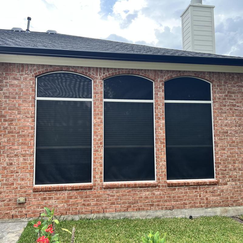Solar window screens installed on brick house facade
