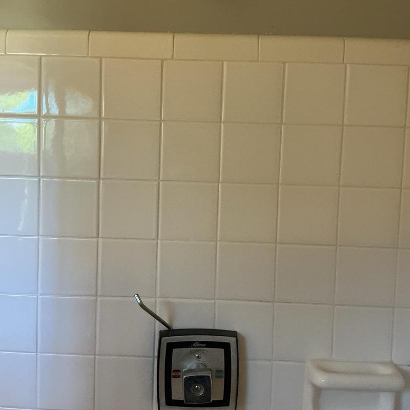 Shower valve with snake tool in tiled bathroom wall